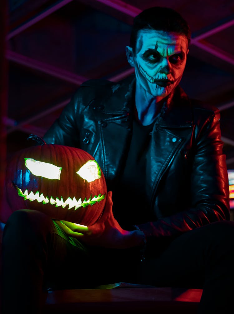 Man In Joker Costume Holding A Pumpkin