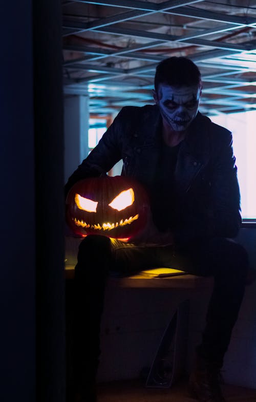 A Man in Black Jacket Holding a Jack O Lantern