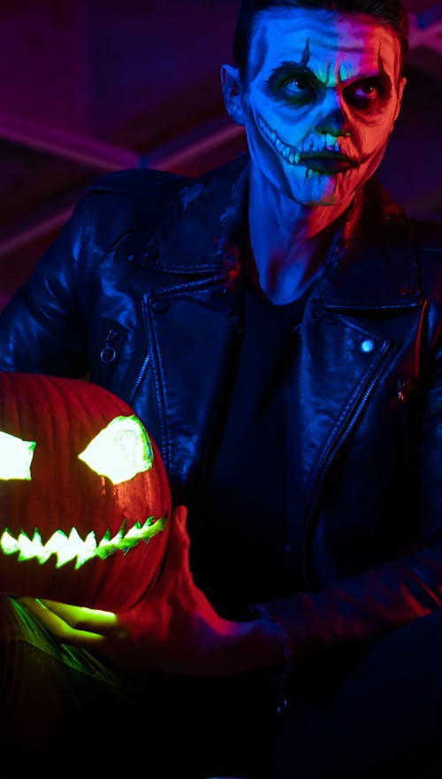 Man in a Halloween Costume Holding a Pumpkin
