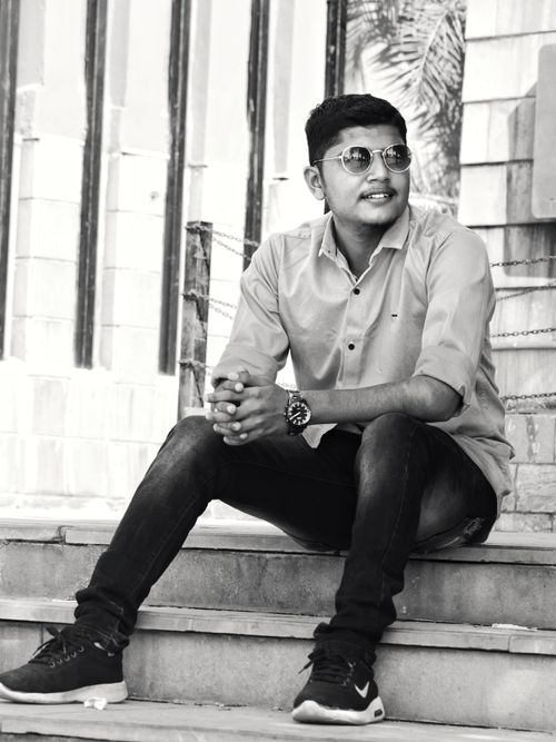 Free Stylish black and white image of a young man sitting casually outdoors. Stock Photo