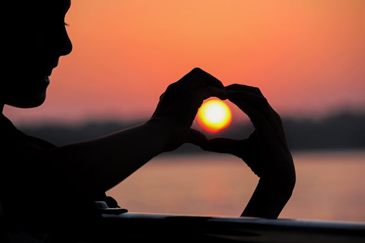 Silhouette Of A Heart Shaped Hands Of A Person Catching The Sunset