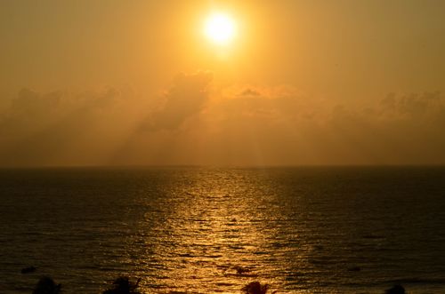 Free A serene sunset casting golden rays over a calm open sea. Stock Photo