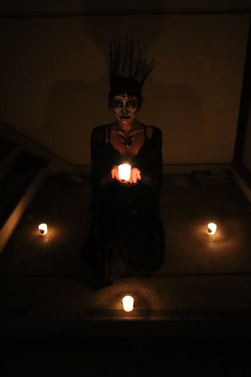 Woman in Scary Costume with Candles in Dark