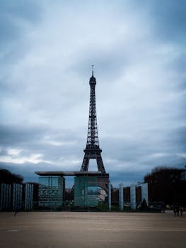 The Eiffel Tower stands tall in Paris with a dramatic cloudy sky, highlighting its iconic structure.