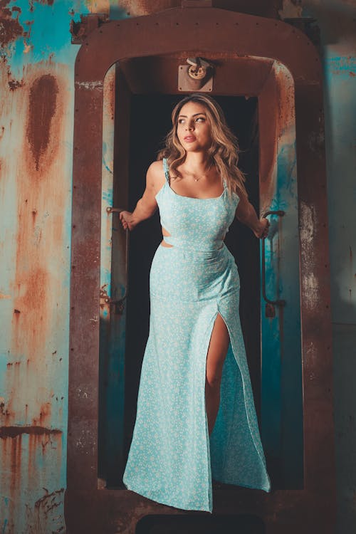 Woman Wearing a Pastel Blue Dress Standing in Rusted Doorway