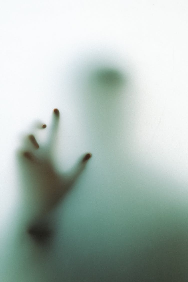 Hand And Silhouette Of Person Behind Glass