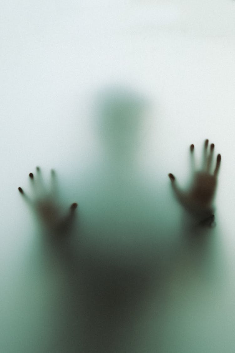 Hands And Silhouette Of Person Behind Glass