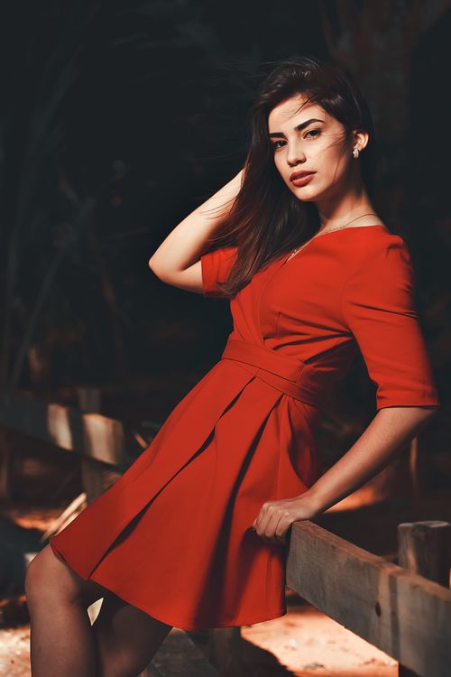 Free Stylish woman poses outdoors in a vibrant red dress with elegant fashion and confident expression. Stock Photo