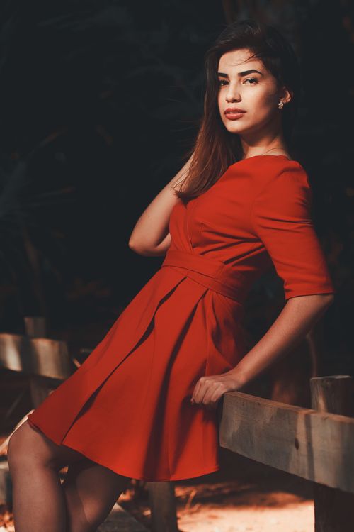 Free Portrait of a woman in a red dress posing elegantly outdoors, conveying a vibrant mood. Stock Photo