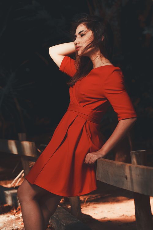 Free Stylish woman in a red dress poses elegantly outdoors, showcasing fashion and grace. Stock Photo