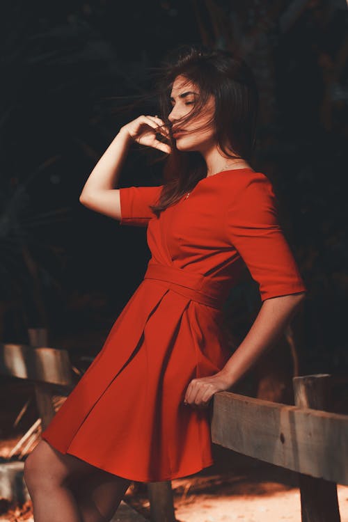 A Woman in Red Dress Leaning on Railing