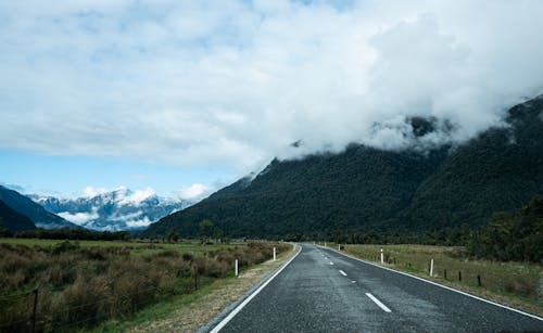 A Gray Asphalt Road Near a Green Mountains 