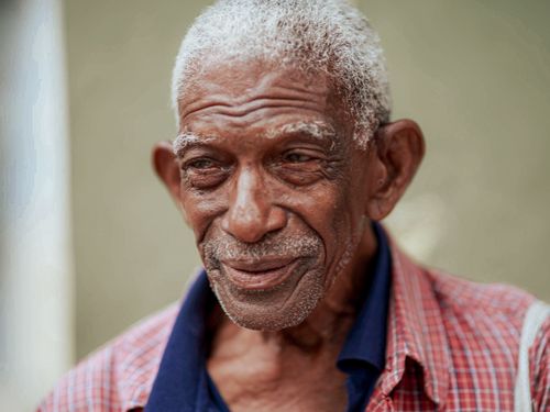Free Close-up of a smiling elderly man with facial hair, wearing a polo shirt. Stock Photo