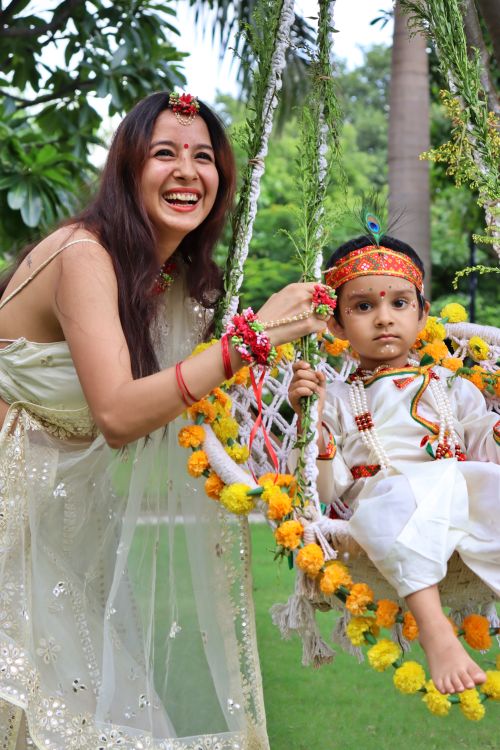 Free A mother and son dressed for Janmashtami celebrate with a swing in a vibrant park setting. Stock Photo