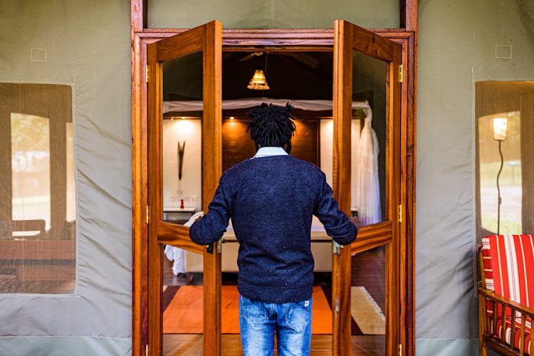 Back View Of A Man Opening A Wooden Door