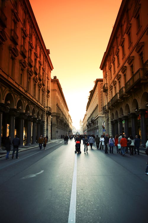 People in Middle of Street Under Orange Sky