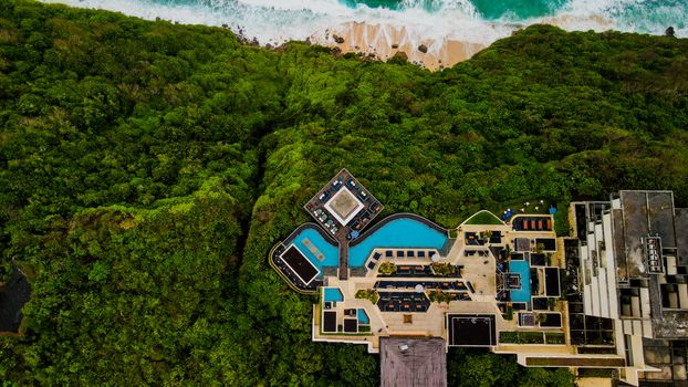 Stunning aerial shot of a luxury resort in Bali, surrounded by lush greenery and ocean view.