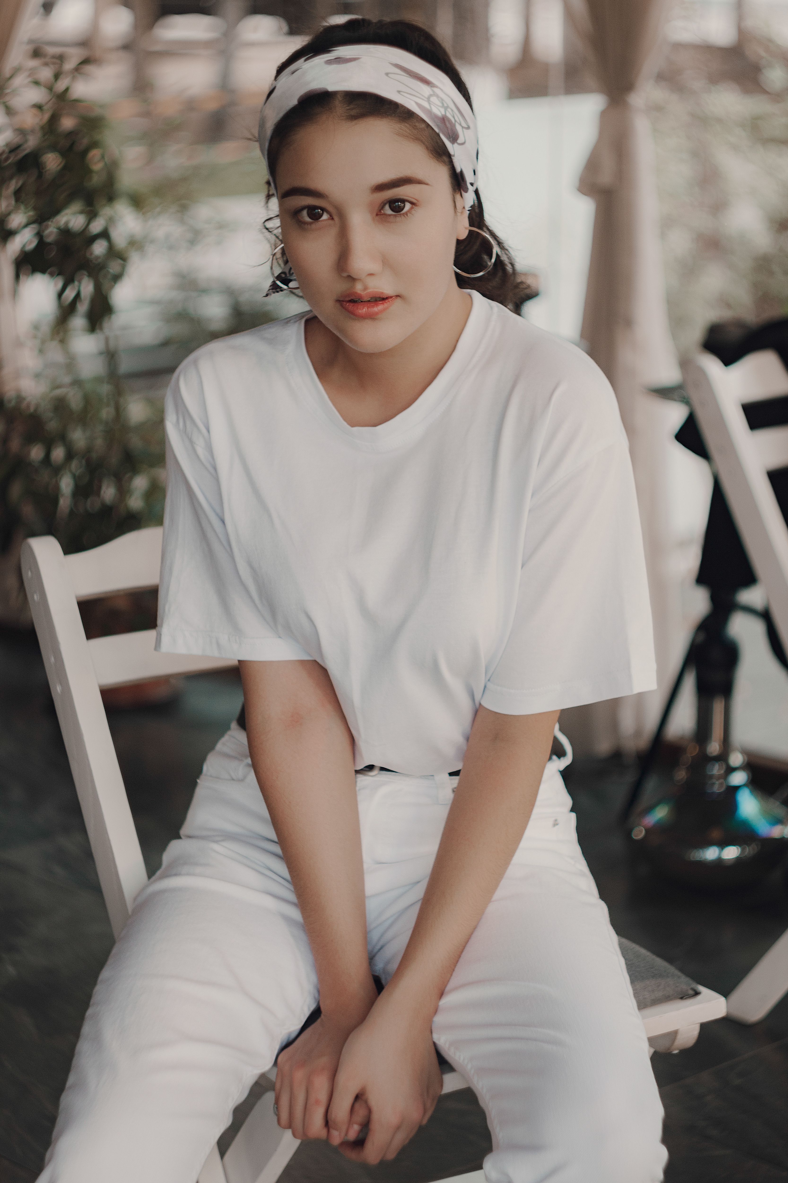 Young woman in white t-shirt and pants posing indoors, exuding casual elegance.