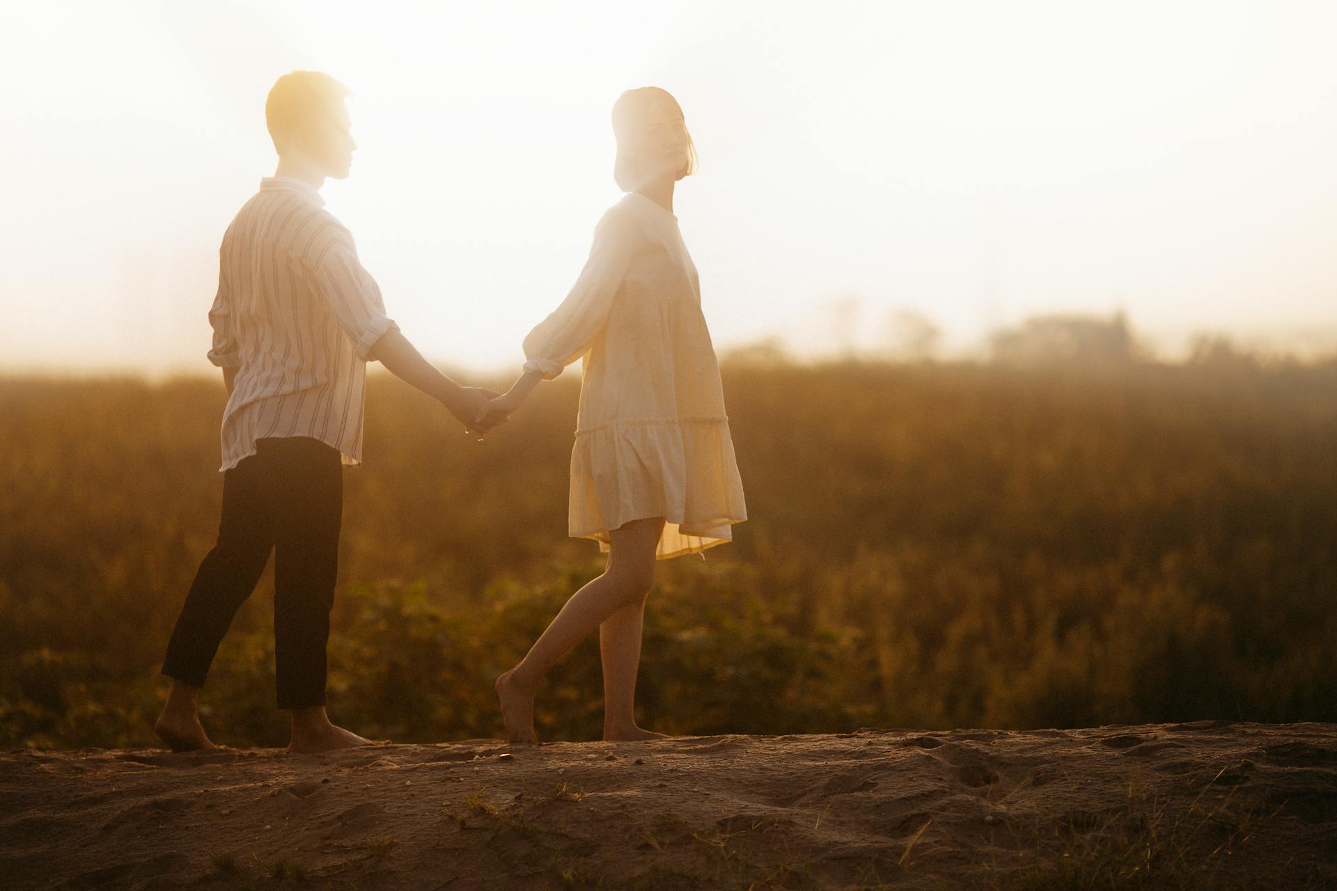 Couple Holding Hands on Sand Field