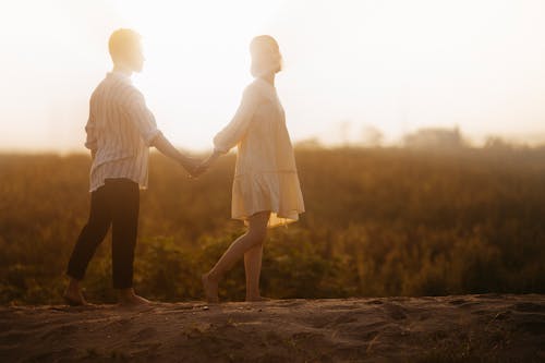 Free Couple Holding Hands on Sand Field Stock Photo
