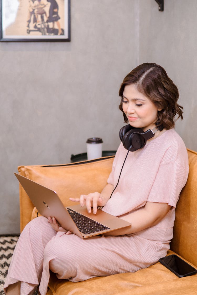 Woman In White Using A Macbook While Sitting On The Sofa