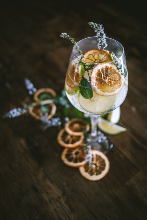 Free Glass of citrus cocktail with dried oranges and herbs on wooden table, creating a rustic feel. Stock Photo