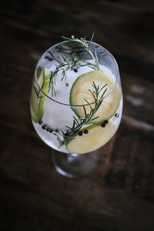Free Close-up of a cocktail garnished with lime slices, rosemary, and peppercorns. Stock Photo