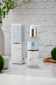 A sleek bottle of skincare product elegantly showcased in a modern white bathroom setting.