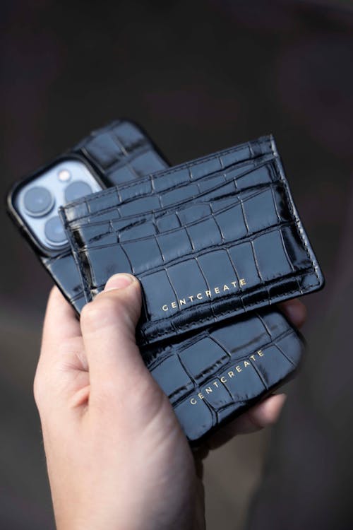 Close-Up Shot of a Person Holding a Wallet and a Smartphone
