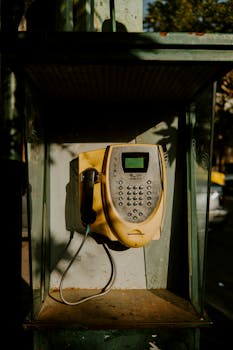 A close-up shot of a classic public telephone in an outdoor urban area.