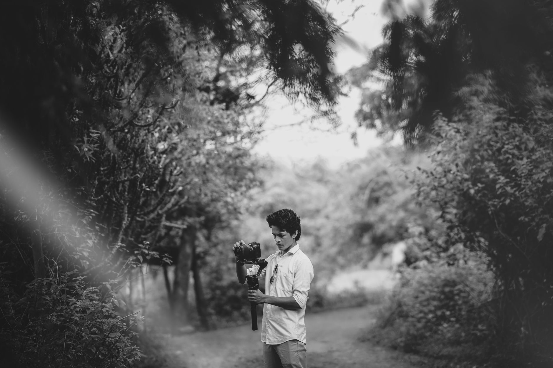 A man holding a camera gimbal in a black and white outdoor portrait.