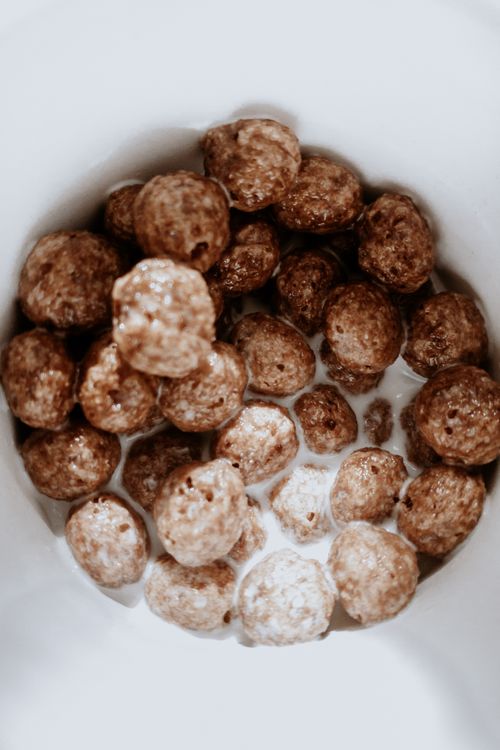 Free Close-up of brown cereal balls in milk within a white bowl, perfect for breakfast imagery. Stock Photo