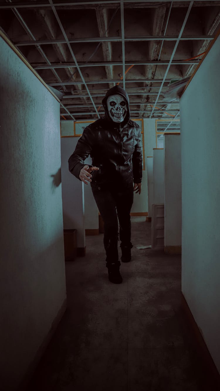 A Man In Black Jacket And Black Pants Wearing Scary Mask