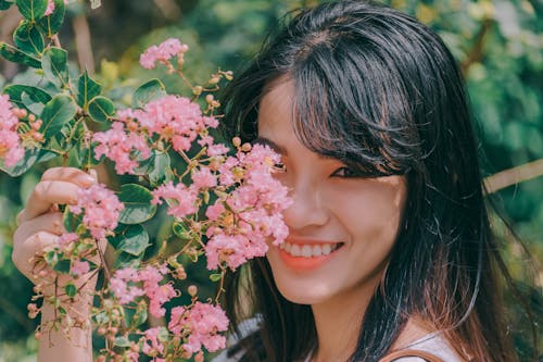 ピンクの栗の花を笑顔で保持している黒髪の女性