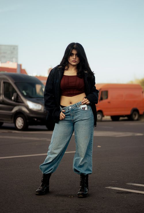 Free Young woman in casual wear posing confidently in a parking lot, showcasing urban fashion. Stock Photo