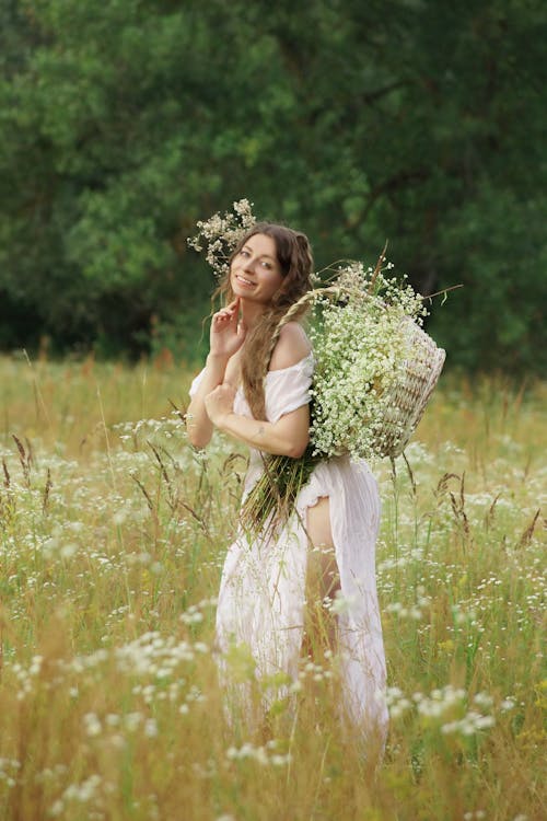 Woman in Dress with Basket of Flowers on Meadow · Free Stock Photo