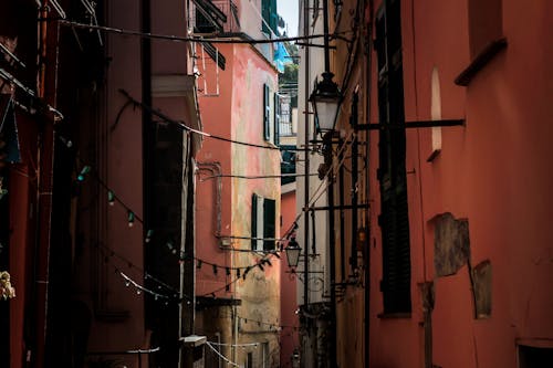 An Alley With Hanging Lights Between Red Buidings