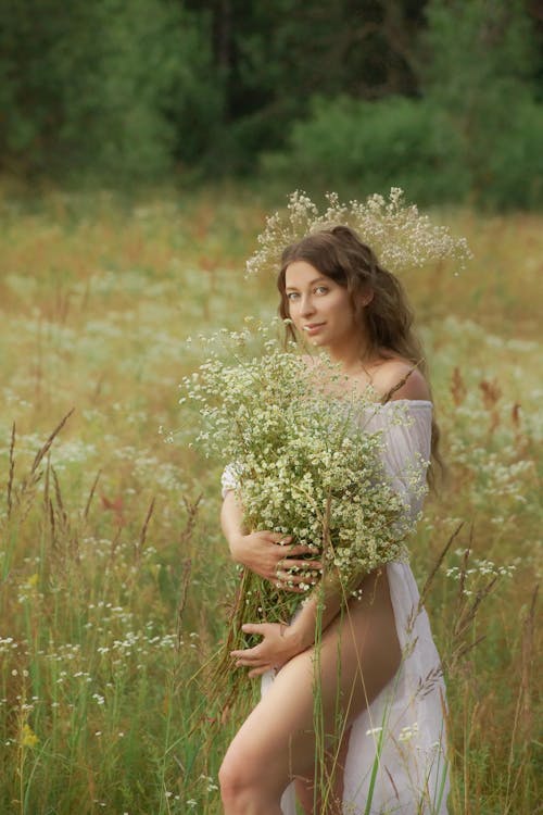 A Woman in White Dress Holding White Flowers