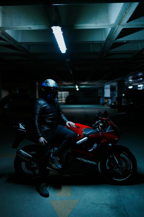 A Man in Black Leather Jacket Riding Red and Black Sports Bike