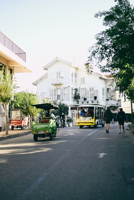 A scenic urban street scene with vehicles and pedestrians under a clear sky.