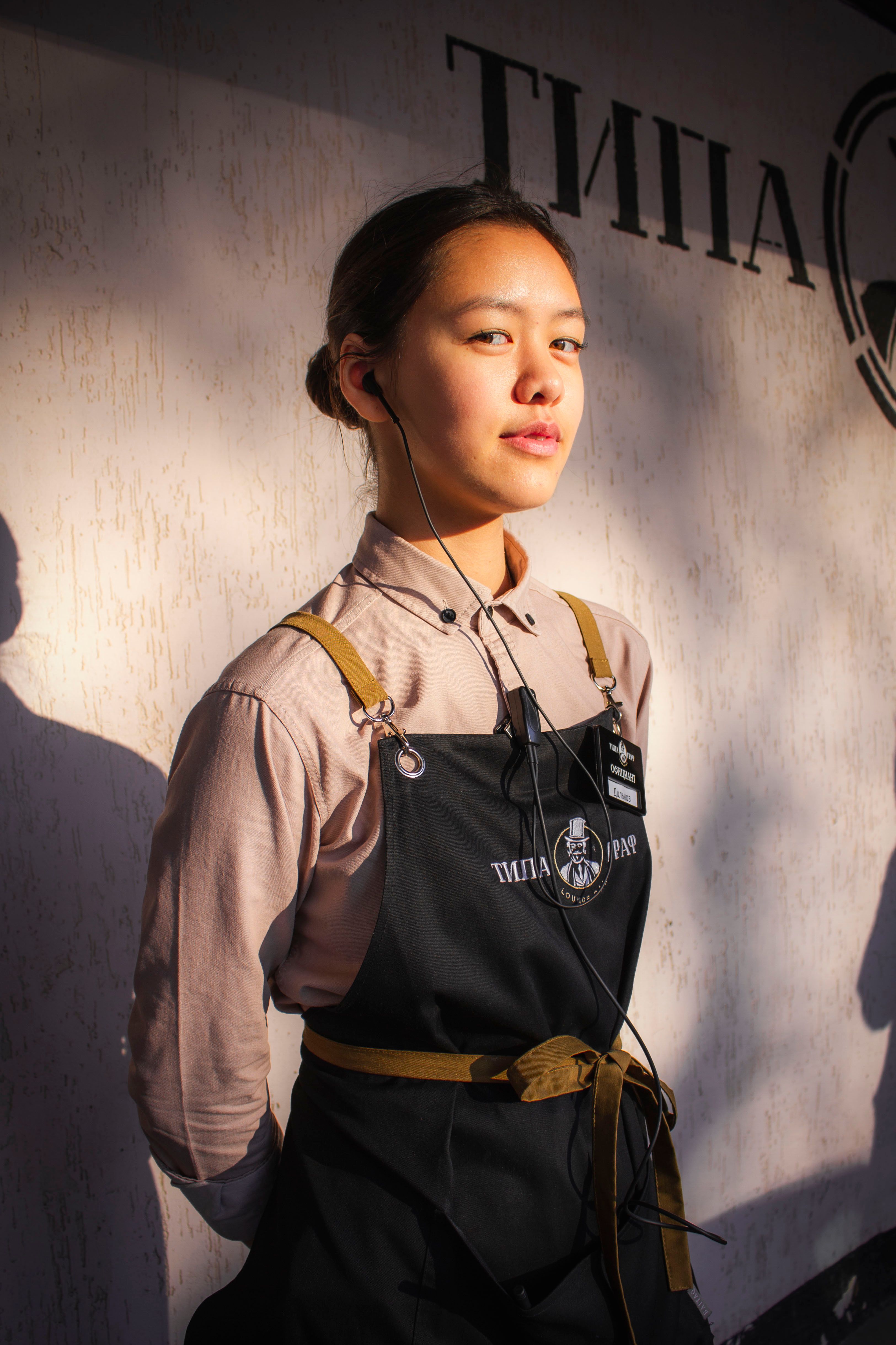 Portrait of a barista standing confidently with a classic coffee shop apron under warm lighting.