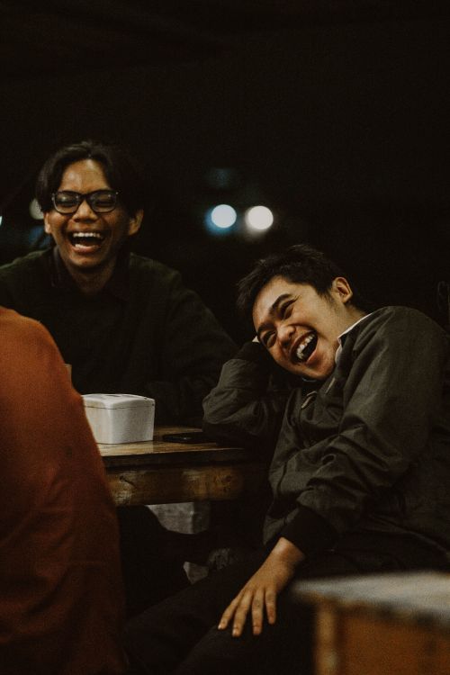 Free Two friends laughing together at a night gathering in Malang, Indonesia. Stock Photo