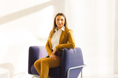 A Woman in Yellow Blazer Sitting on a Sofa Chair