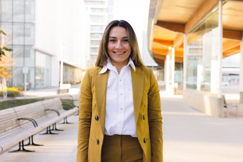 Woman Smiling in Mustard Blazer and Pants Standing Outside an Office Building