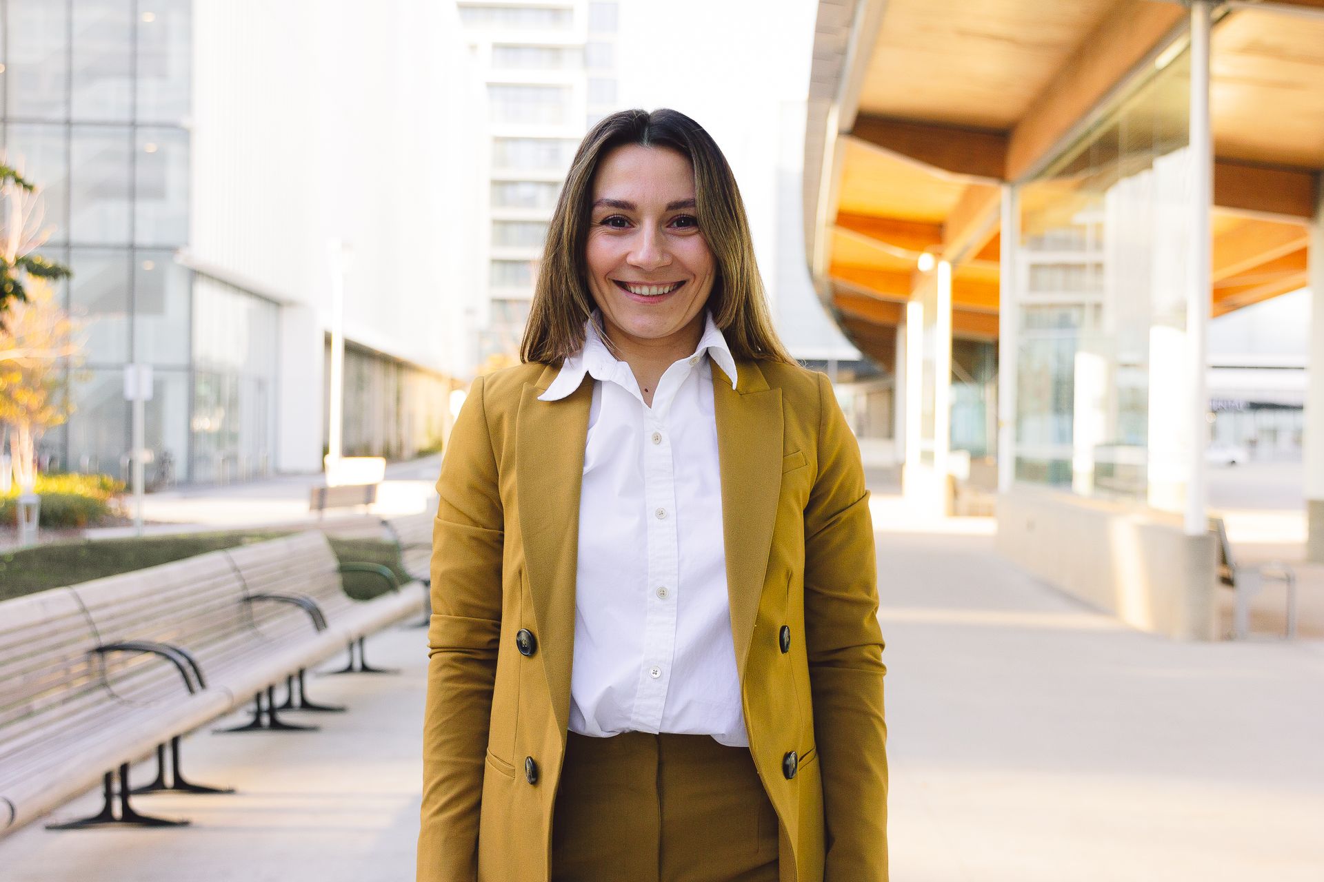 Woman Smiling in Mustard Blazer and Pants Standing Outside an Office Building