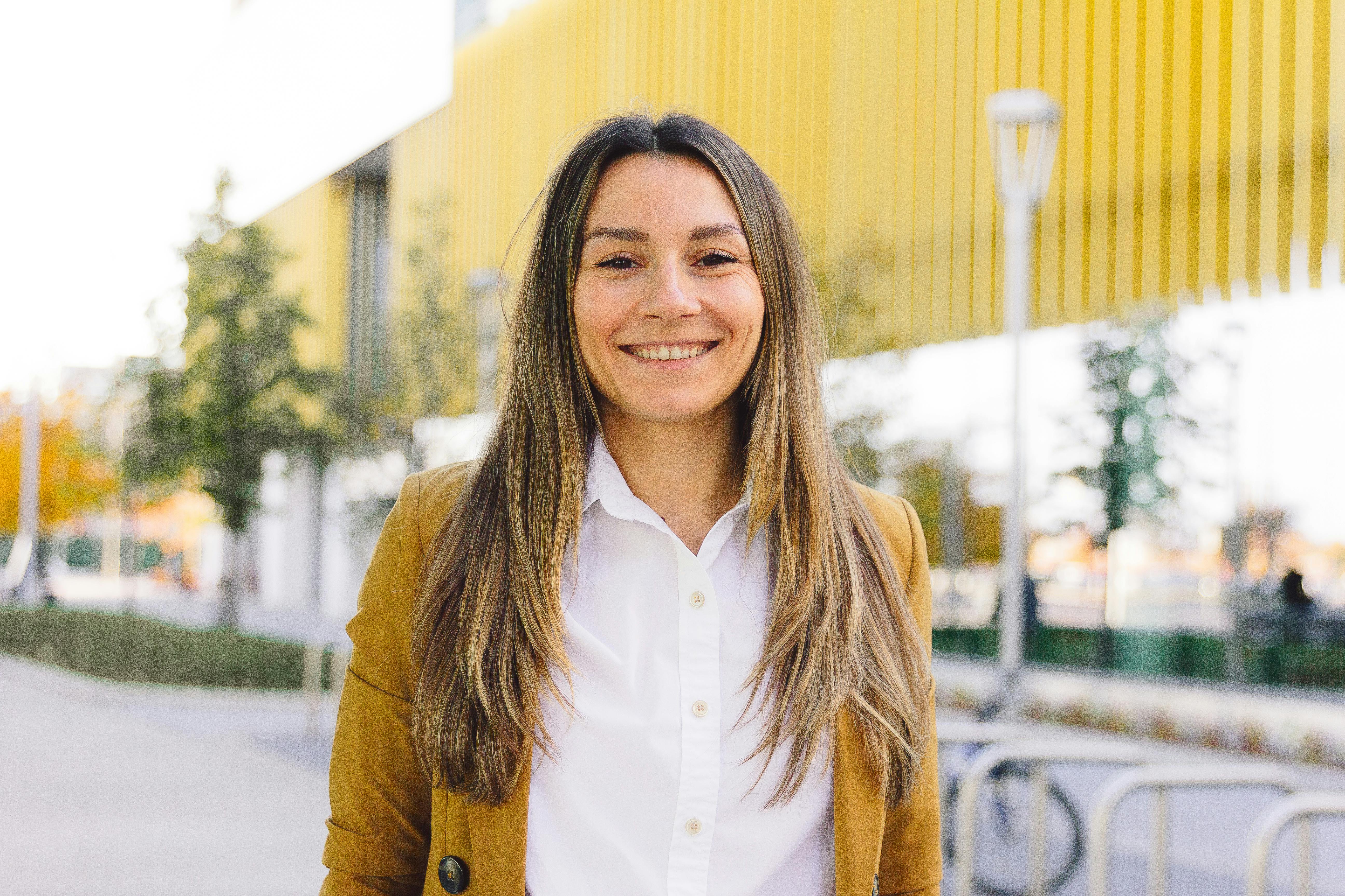 Ofis masasında dik bir postürle oturan, kendinden emin ve özgüvenli bir duruş sergileyen genç bir profesyonel.