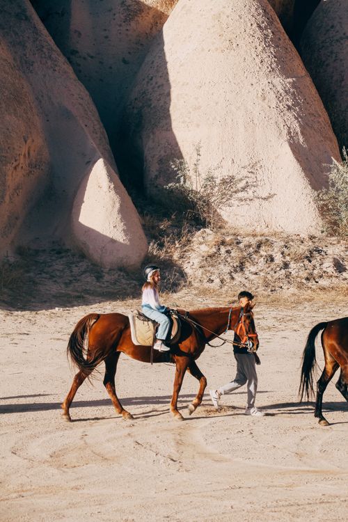 Free A child enjoys horseback riding in the scenic rock formations of Göreme, Turkey. Stock Photo