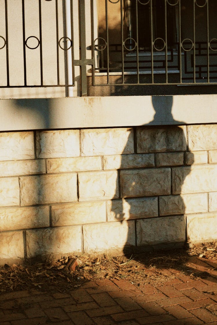 A Shadow Of A Person In A Brick Concrete Wall