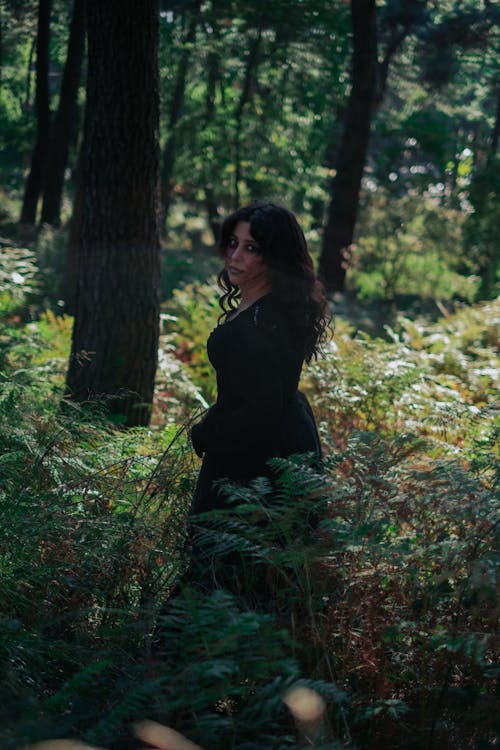 Premium Photo  A woman in a black robe stands in a dark forest.