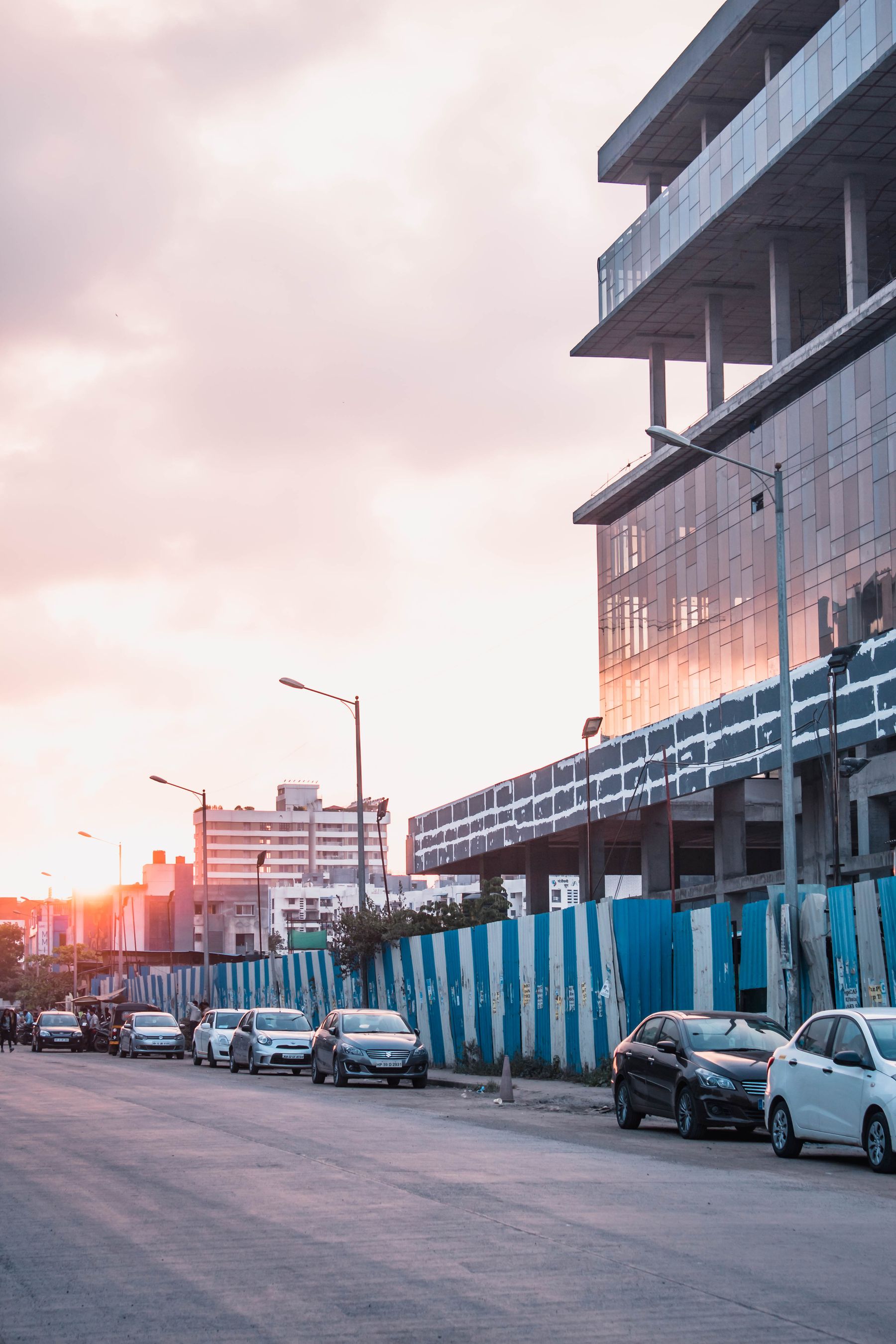 Pune street at sunset with parked cars and buildings under construction